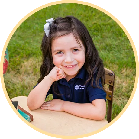 Smiling girl resting chin on hand.