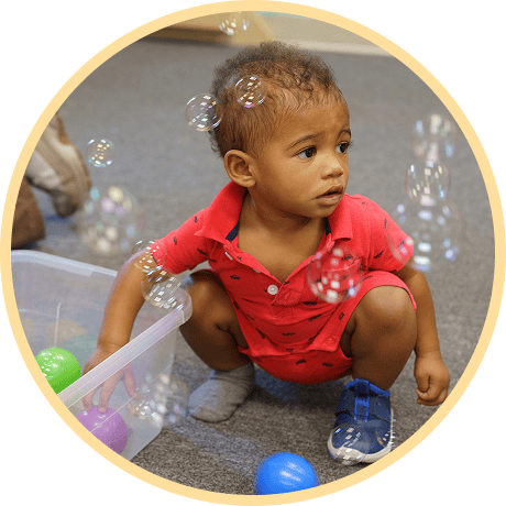 Toddler observing bubbles in a classroom