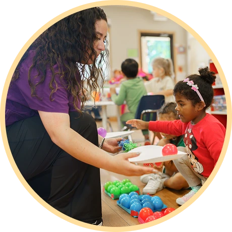 Instructor assisting child with colorful play materials.