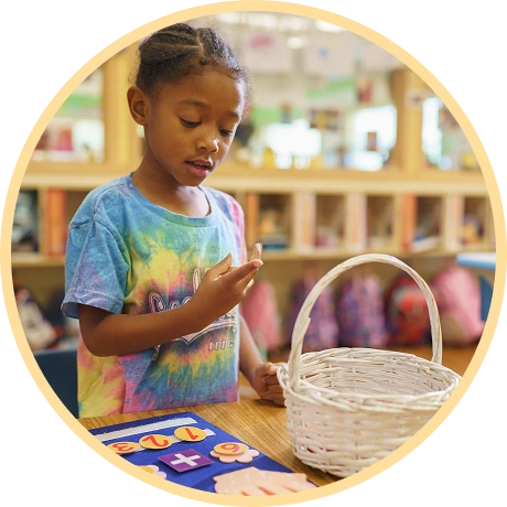 Child exploring objects at a classroom table.